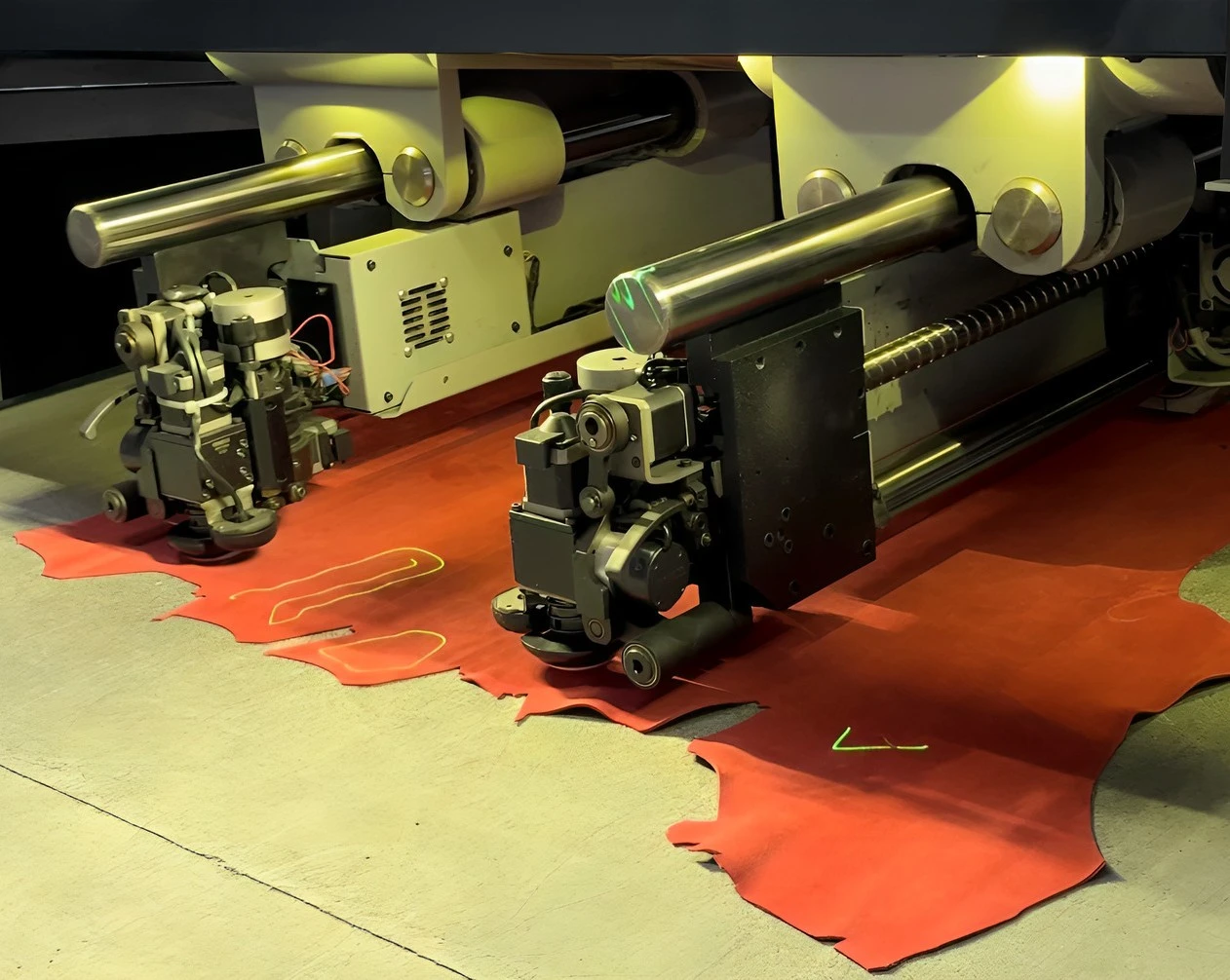 Automated laser cutting machine working on red fabric at a Portugal clothing manufacturer using advanced textile production technology.