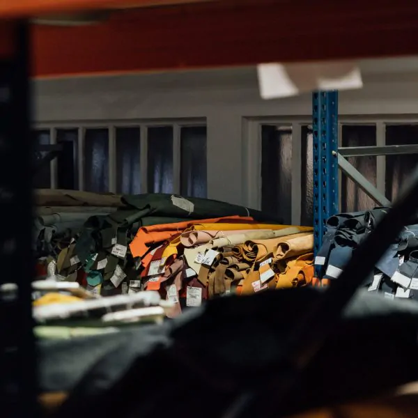 Stacks of colorful fabric rolls organized on shelves at a Portugal clothing manufacturer’s warehouse, labeled and ready for apparel production