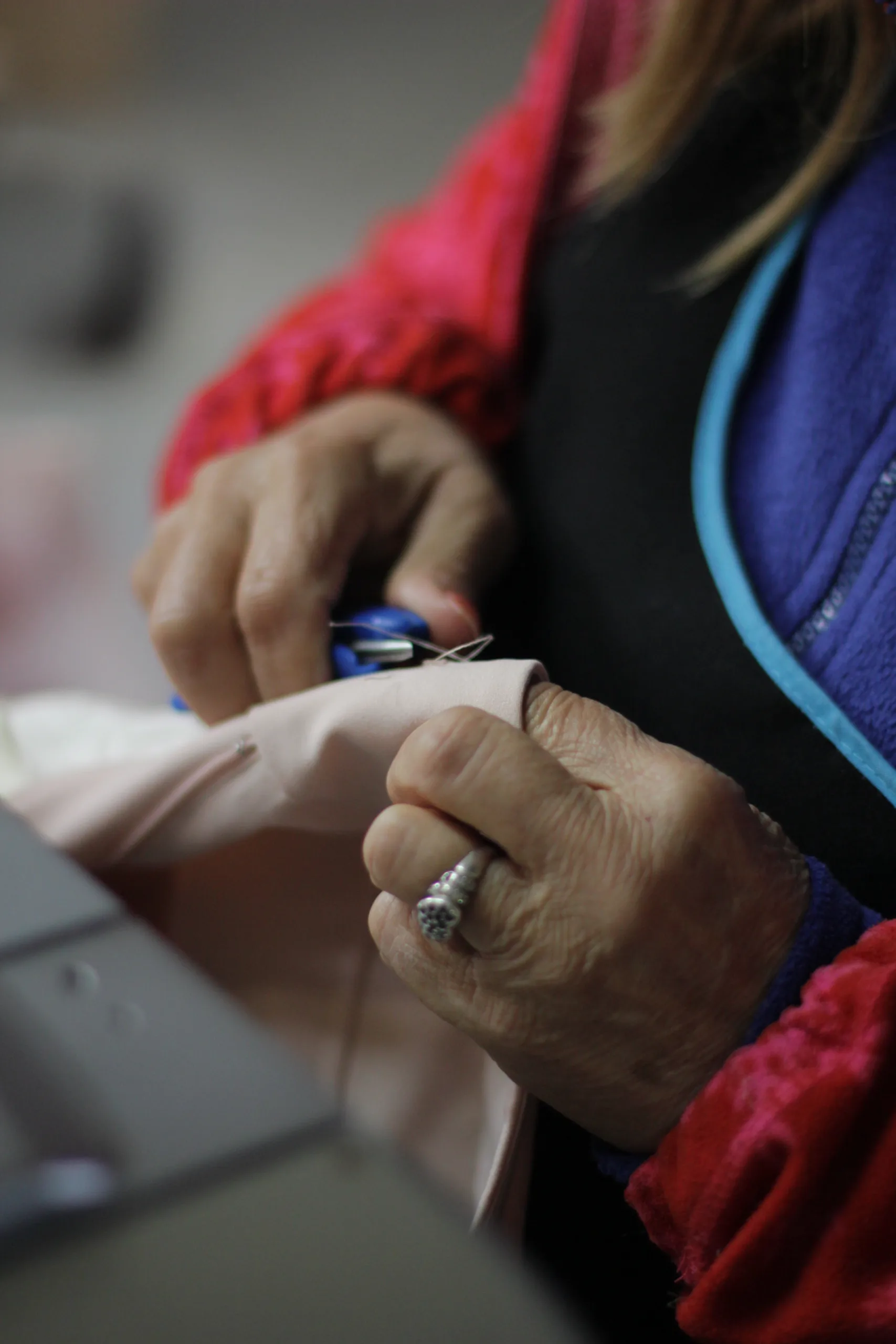 Close-up of a women worker sewing fabric by hand at a Portugal clothing manufacturer using ethical and sustainable production practices.