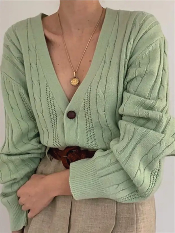 Knitwear Trends To Keep Cozy This Winter. Green cardigan with beige pants.