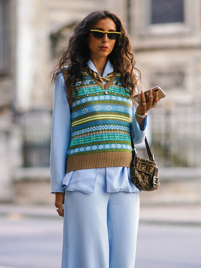 Knitwear Trends To Keep Cozy This Winter. Coloured sweater vest over blue shirt and pants.