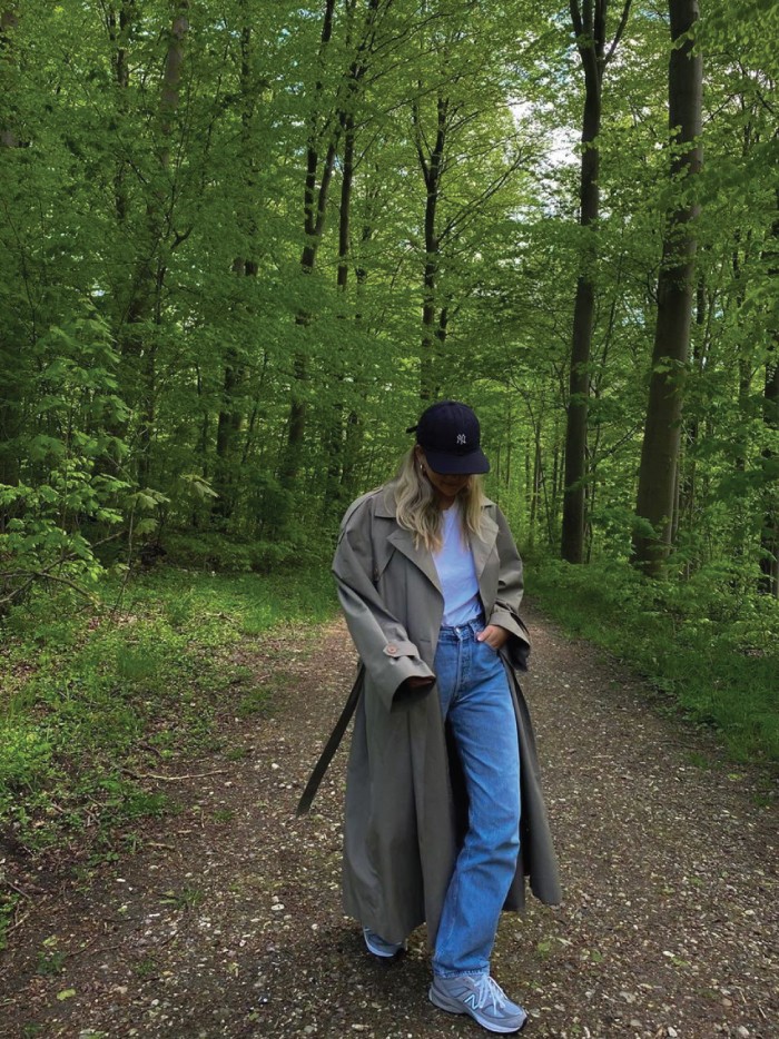 Trends to wear with jeans: baseball hats. Jeans, sneakers, a long coat and a black baseball hat.