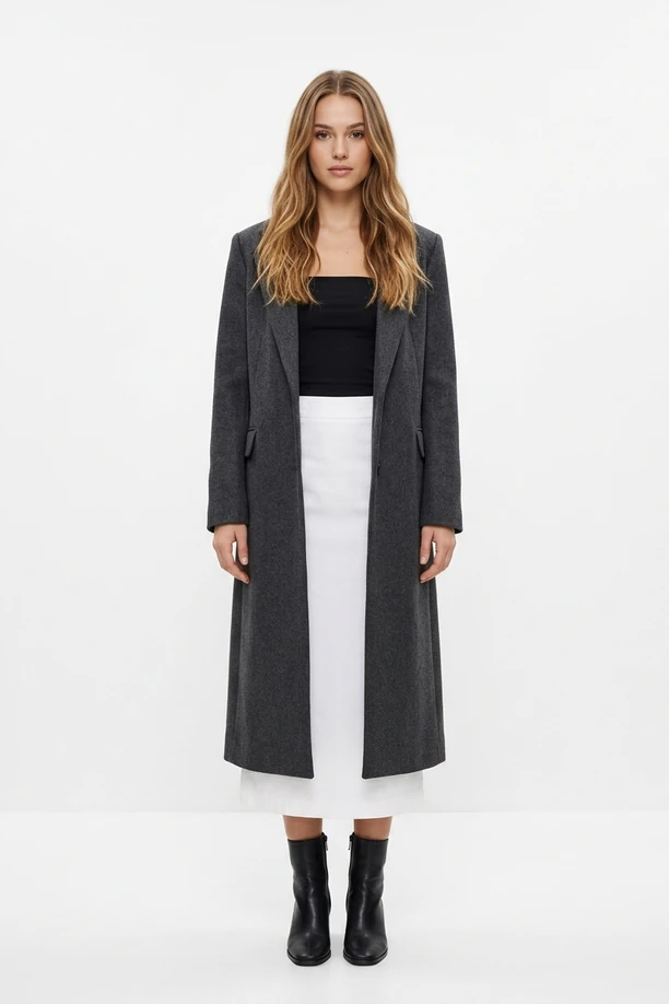 Mannequin en long manteau duster gris anthracite, bustier noir et jupe midi blanche.