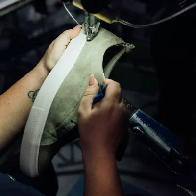 Person making a shoe sample in a machine at a factory.